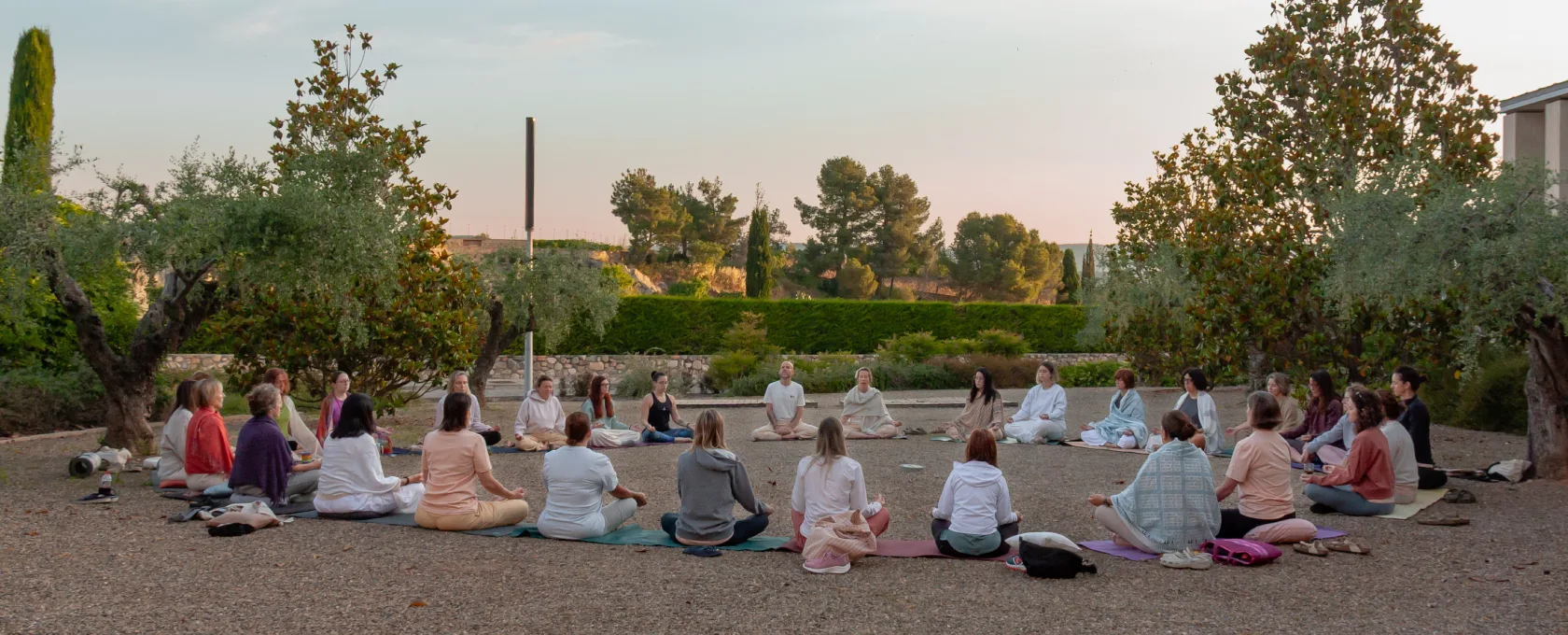 Grupo practicando meditación sentada en círculo al aire libre durante un retiro de yoga